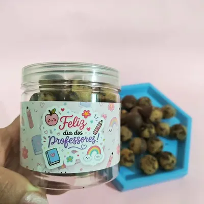 Pote transparente cheio de cookie balls com rótulo colorido, ao lado de uma bandeja azul com mais bolinhas