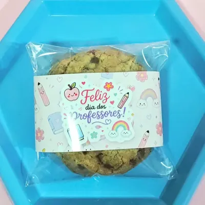 Cookie com gotas de chocolate embalado em saquinho com rótulo colorido, sobre bandeja azul